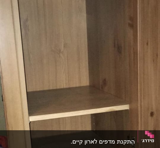 ארון עץ עם מדפים ריקים ודלת פתוחה